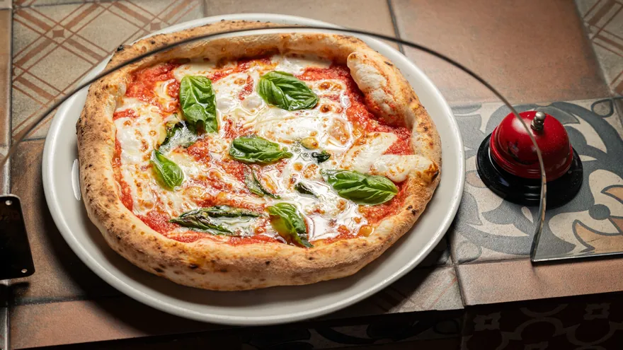 Una pizza margherita nel piatto, con basilico fresco
