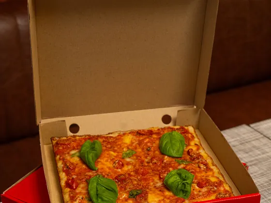 Una pizza dentro la scatola d'asporto rossa aperta